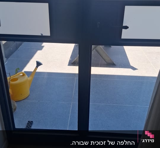 חלון זכוכית עם נוף לחצר ומזלף צהוב